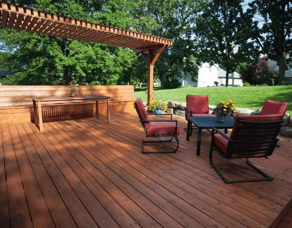 Custom wood deck and pergola built in Rexburg, ID with patio furniture and landscaped yard