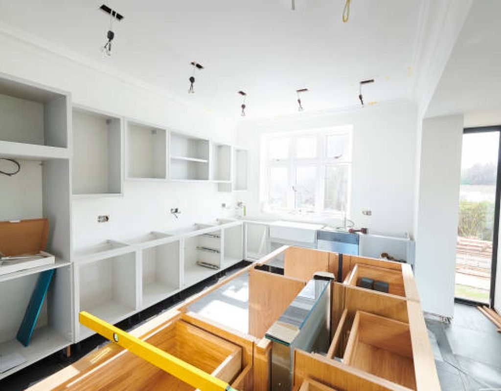 Skilled remodeler checking cabinet alignment and kitchen measurements with precision tools